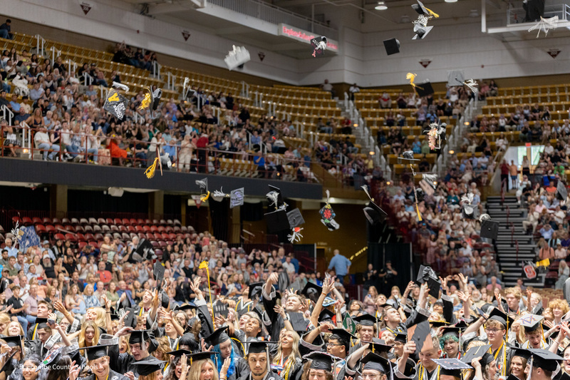 Members of the North Buncombe High School class of 2025 toss their graduation caps into the air.