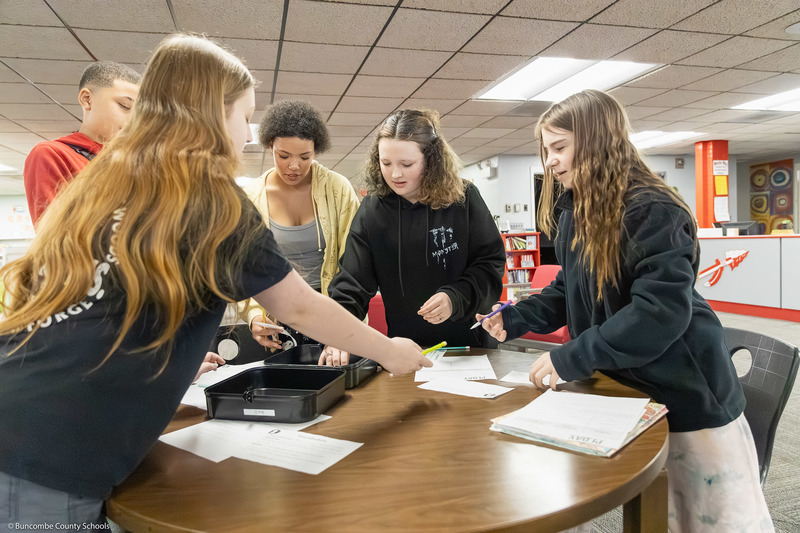 Students open one of the breakout boxes on a table.