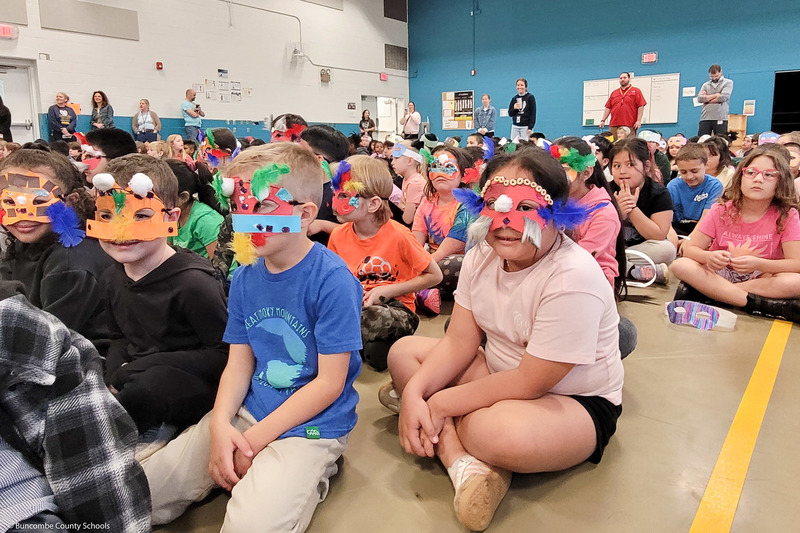 Students wear creative masks during a school assembly.