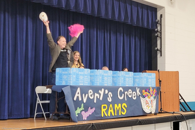 A "masked reader" reveals himself to students during an assembly.
