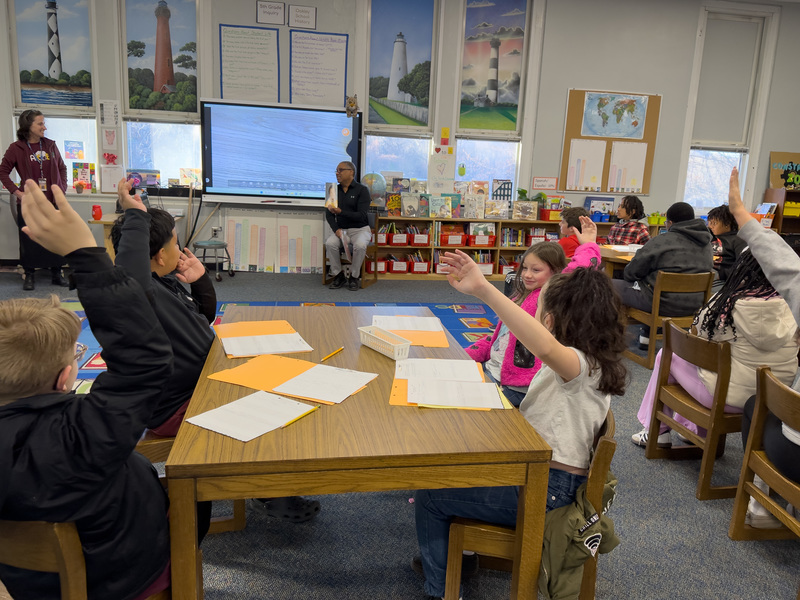 Photo of a bunch of students raising their hands to ask Rev. Martin a question. 