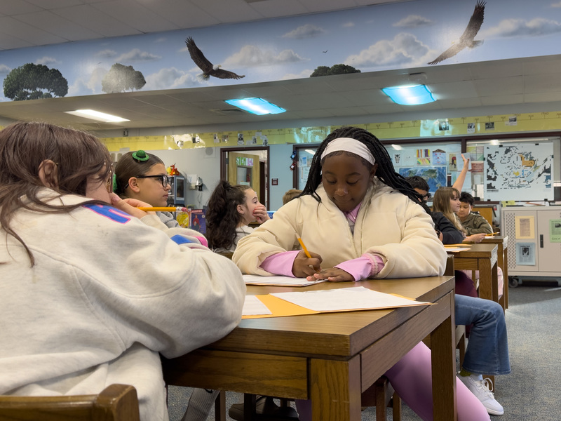 Female student taking notes and listening to what Rev. Martin has to say. 
