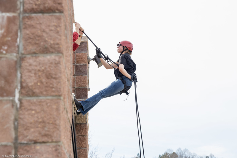 A student prepares to rappel down the tower.