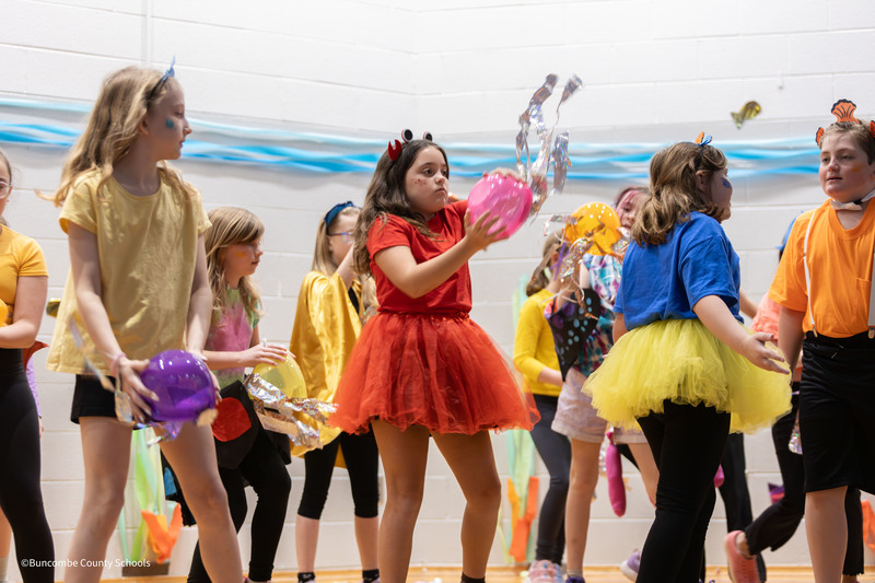 Students dressed in various ocean costumes on stage dancing
