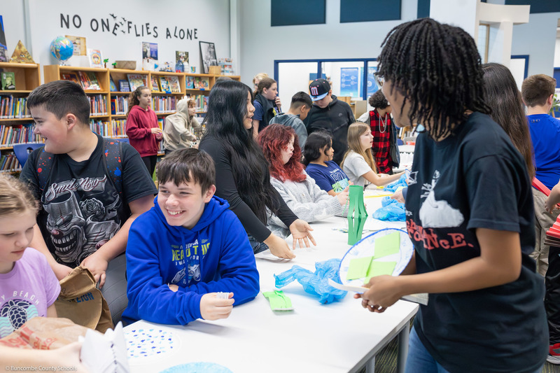 Students trade items with one another, creating a hustle and bustle of tables resembling a marketplace.