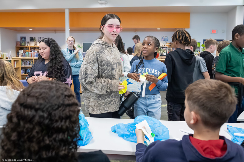 Students trade items with one another, creating a hustle and bustle of tables resembling a marketplace.