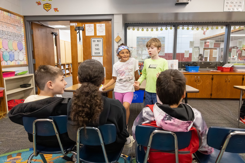 A girl and boy talk to other students about their projects.