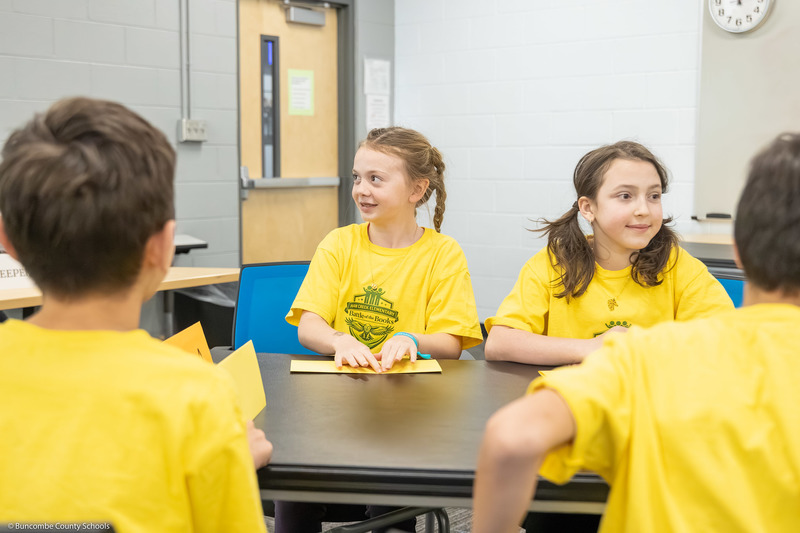 Two Haw Creek Elementary students smile while sitting at a table.