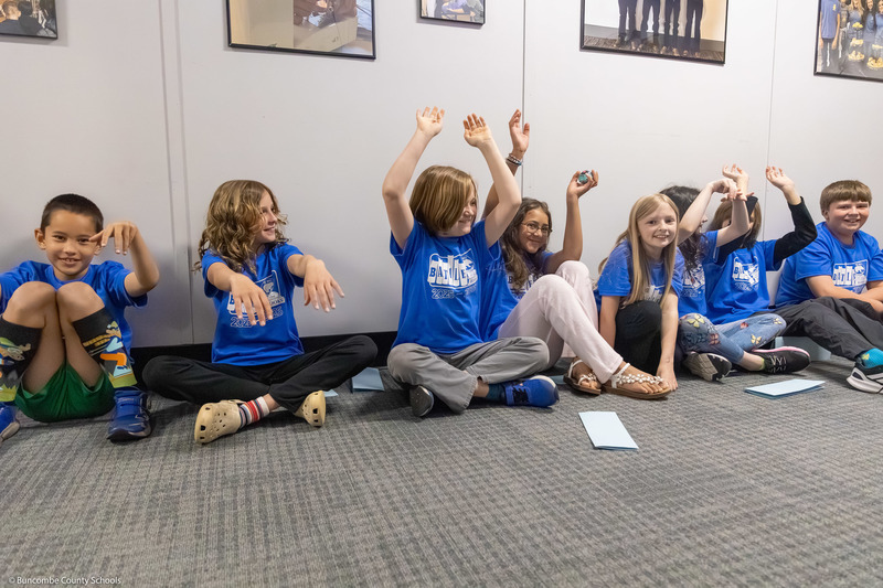 Students do "the wave" in a hallway.