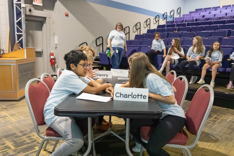 Students lean in to confer at a table during the competition.