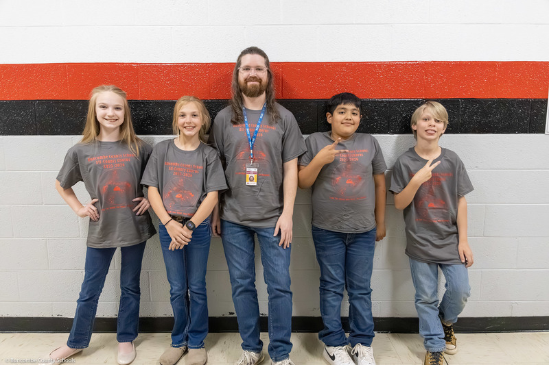 Four students pose in a hallway with a teacher.
