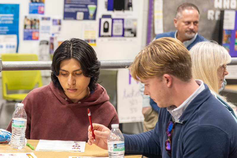 Two student members of the advisory council read fact sheets and prepare to write.