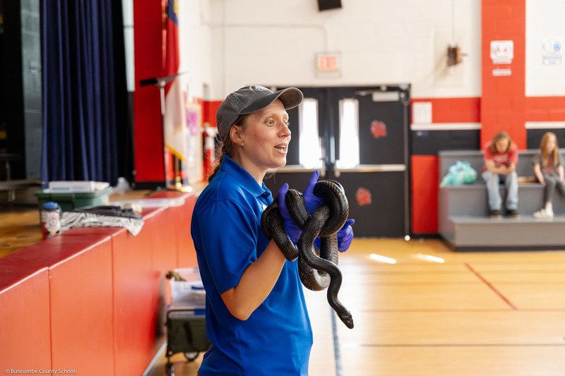 A WNC Nature Center representative holds a black snake.