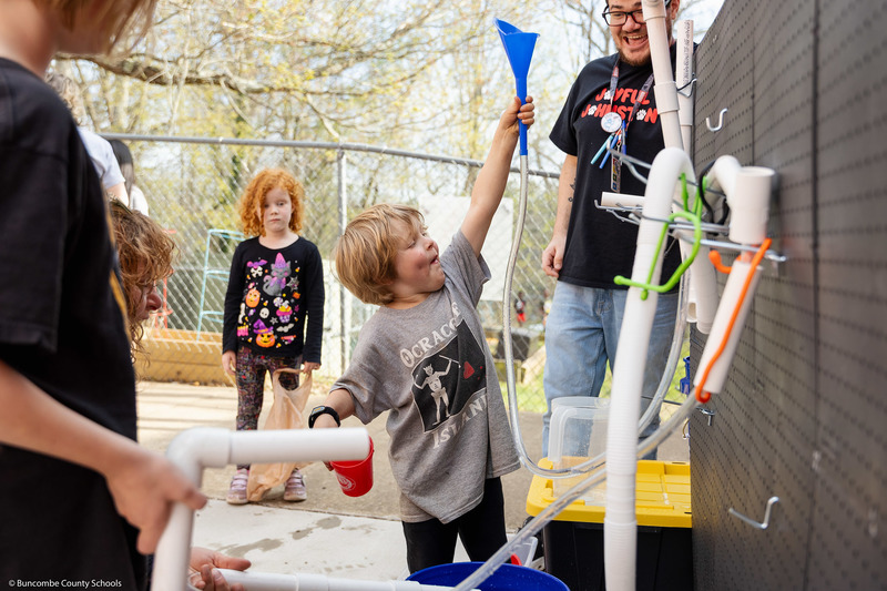 A student holds up a funnel as part of a water properties demonstration.
