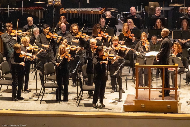 Strings musicians stand to demonstrate their instruments.