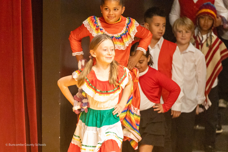 Two girls in colorful dresses prepare to run and take their spots on stage.