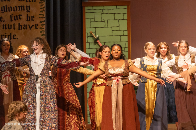 A group of people in renaissance clothing dancing on stage.