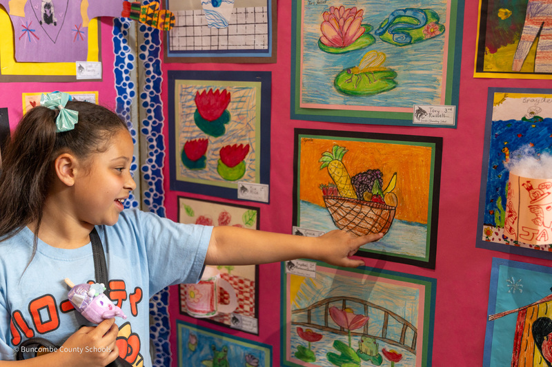 A student points to the fruit basket drawing she created.
