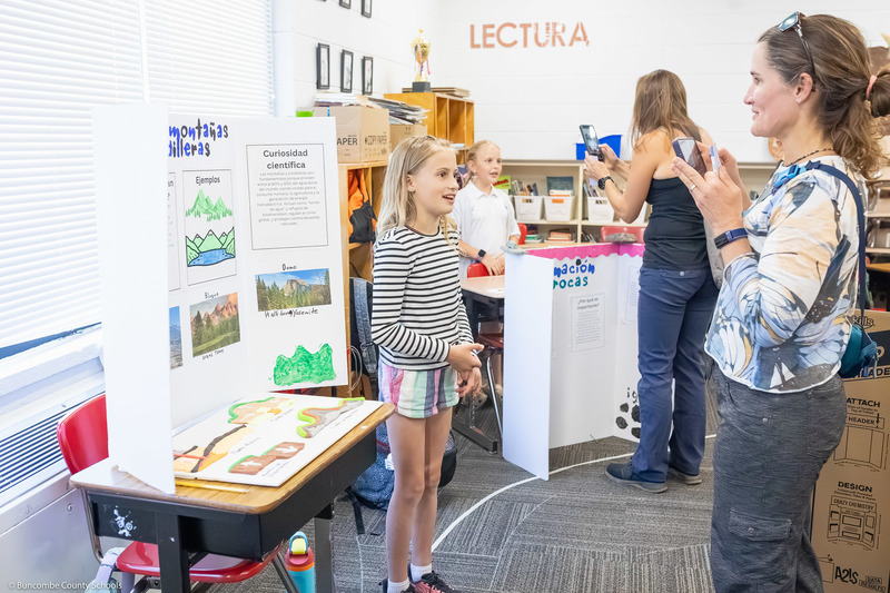 A girl speaks to a woman about her presentation.