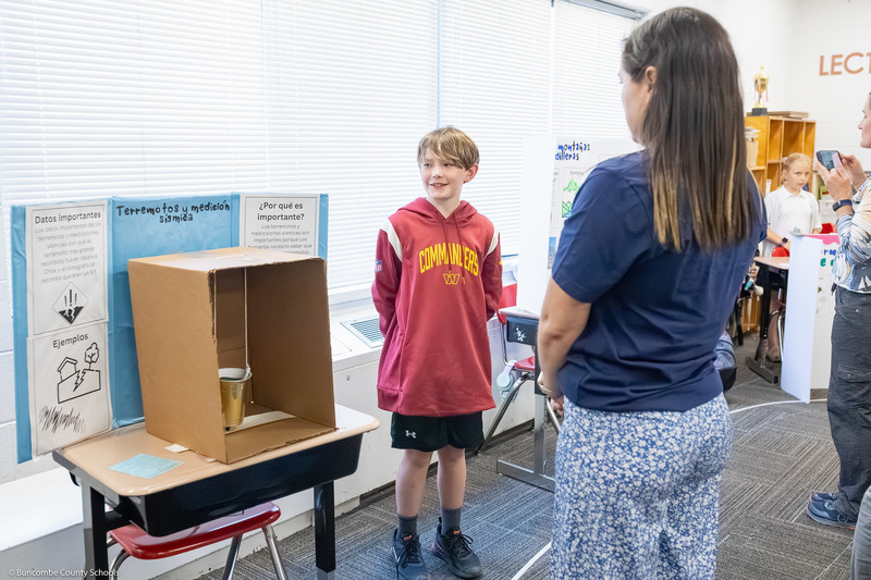 A boy speaks to a woman about her presentation.