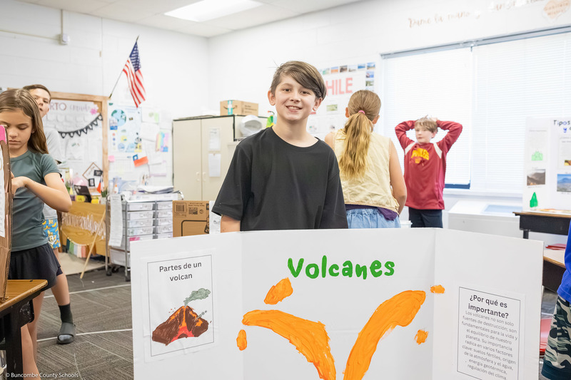 A boy poses behind a volcano presentation.