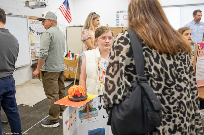 A girl speaks to a woman about her presentation.