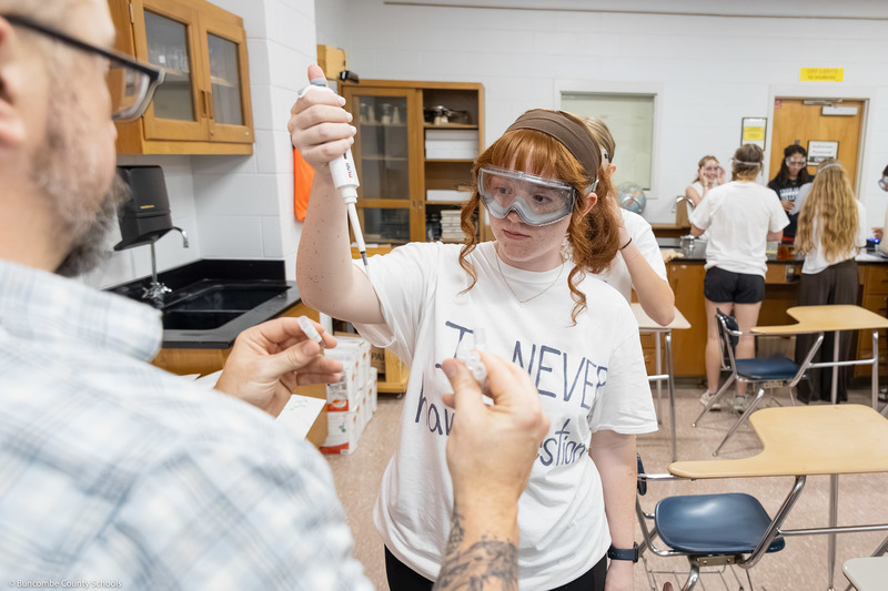 Ryan Smith holds a DNA sample while a student extracts liquid.