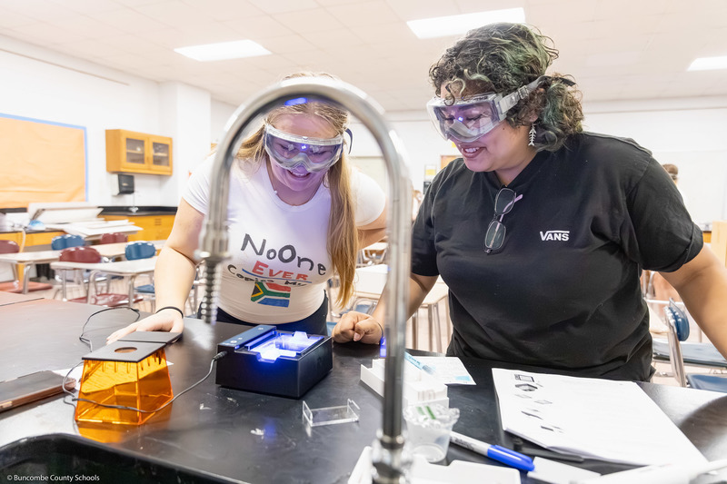 Two students, wearing safety goggles, work on a DNA test.