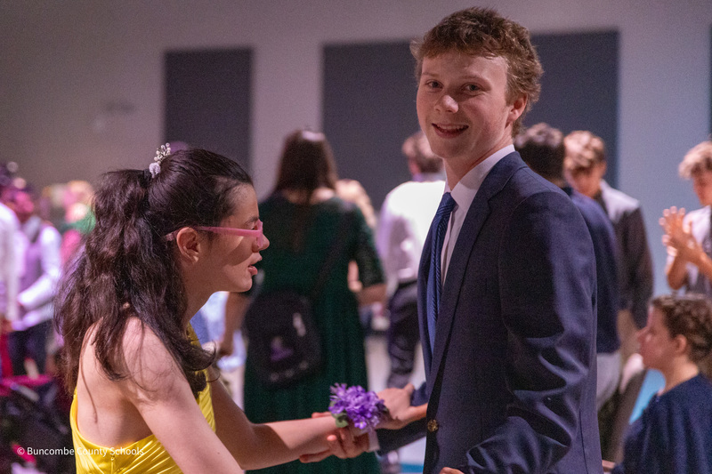 A PEP student in a yellow dress dances with her peer tutor, who is in a suit.