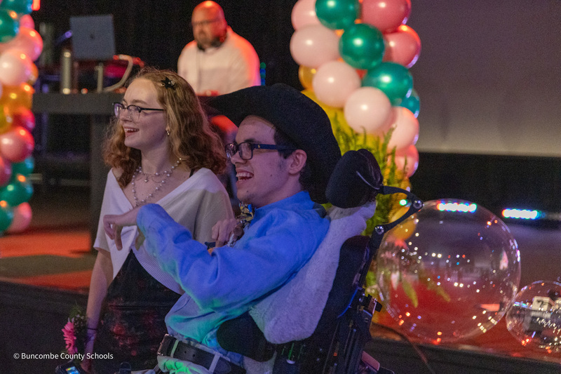 A PEP student in a cowboy hat and his peer tutor smile in front the DJ.