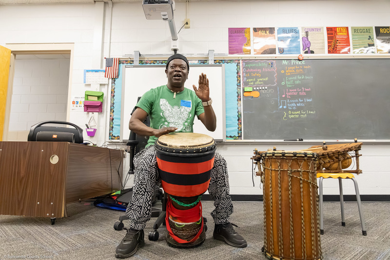 Adam Dembele leads a class through a hand drum routine in Preston Prince's music class.