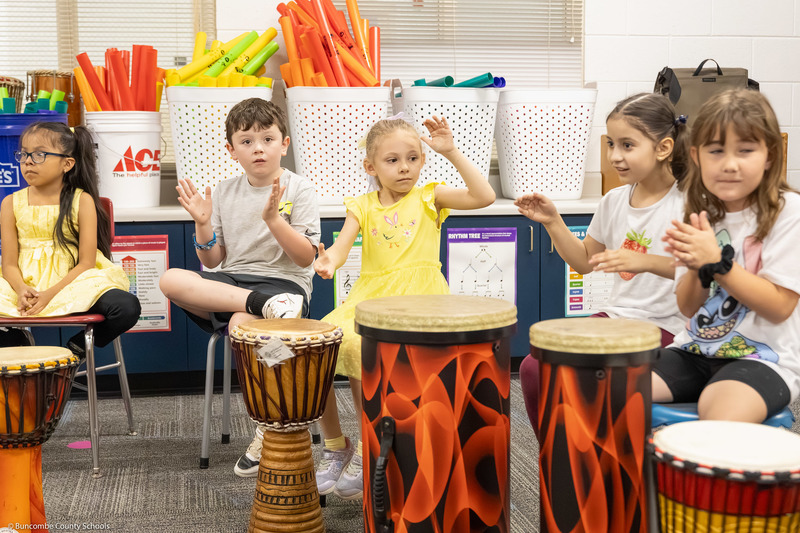 Students play hand drums in music class.