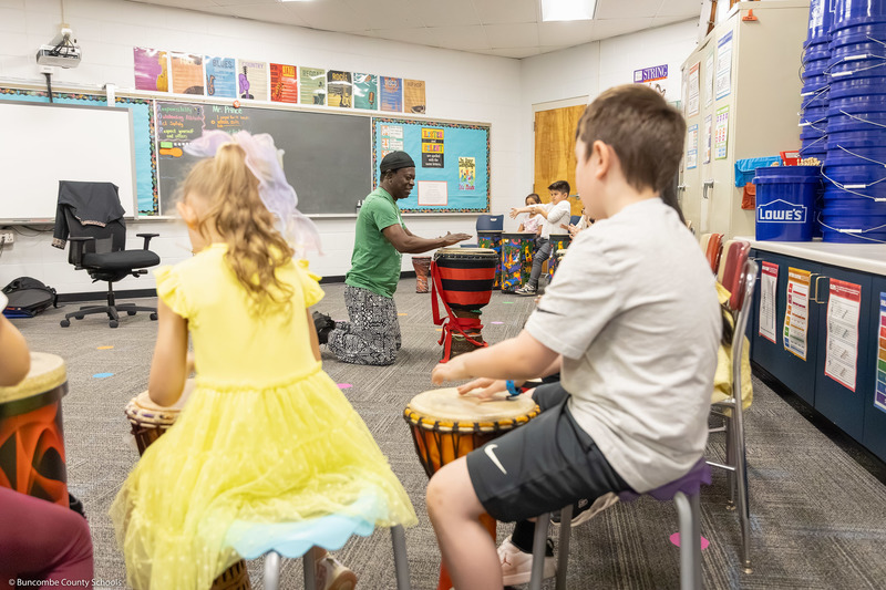 Adam Dembele leads a class through a hand drum routine in Preston Prince's music class.