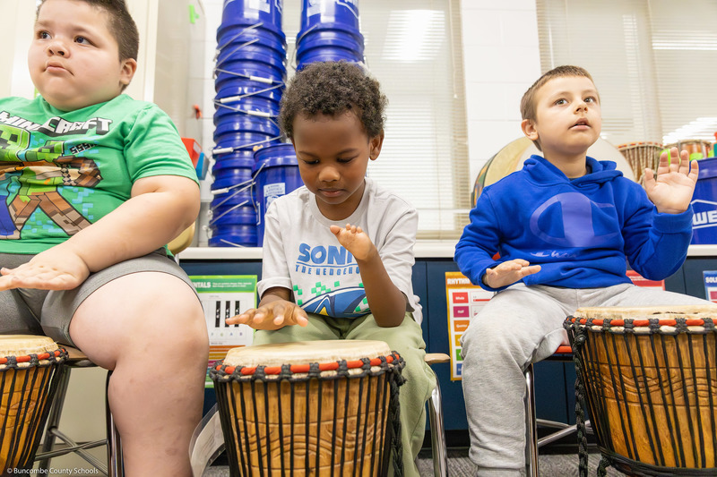 Students play hand drums in music class.