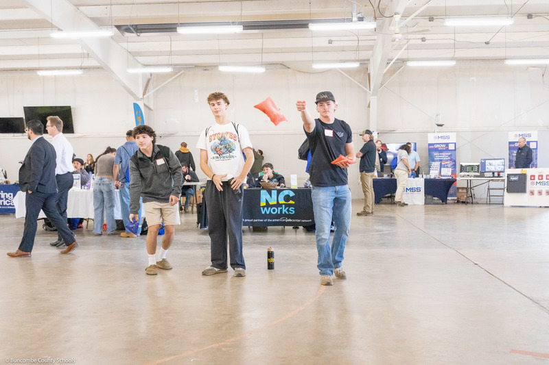 Three students play cornhole