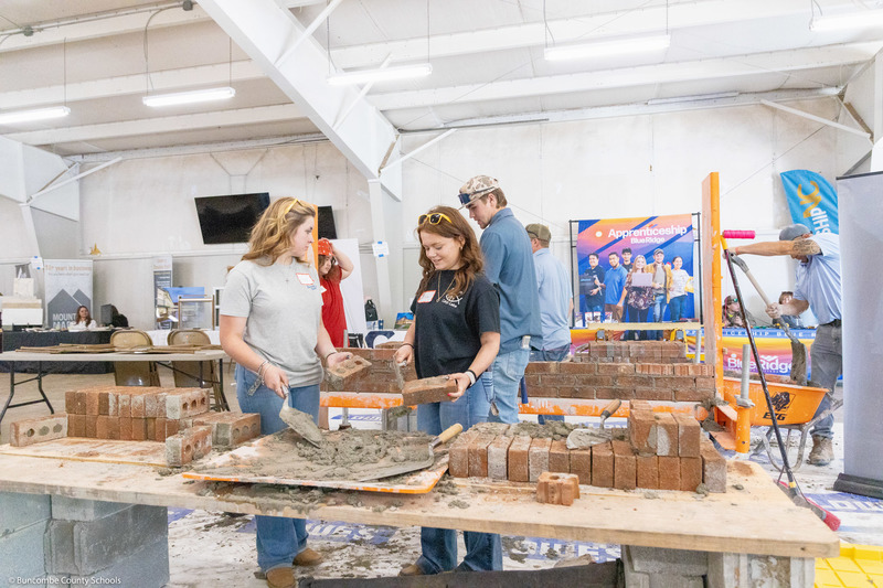 Two students practice bricklaying.