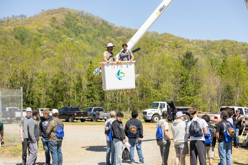 A student stands in the bucket of a utility truck.