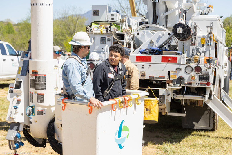 A student stands in the bucket of a utility truck.