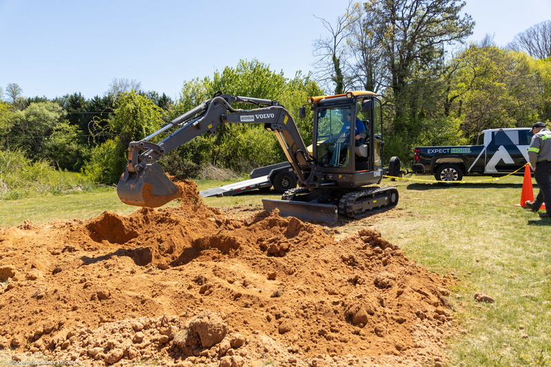 A student digs a hole with a backhoe at the fairgrounds.