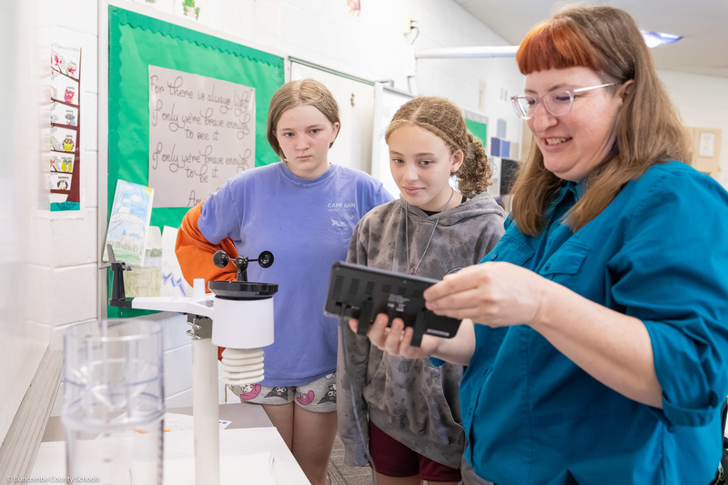 Students look at a weather station with one of the presenters.
