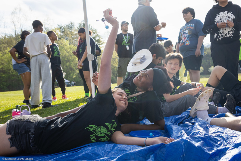 Two students smile while laying on a tarp.