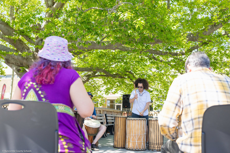 Visitors participate in a drum circle.