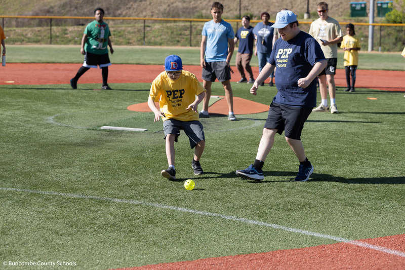 Students running to pick up a ball on the field. 