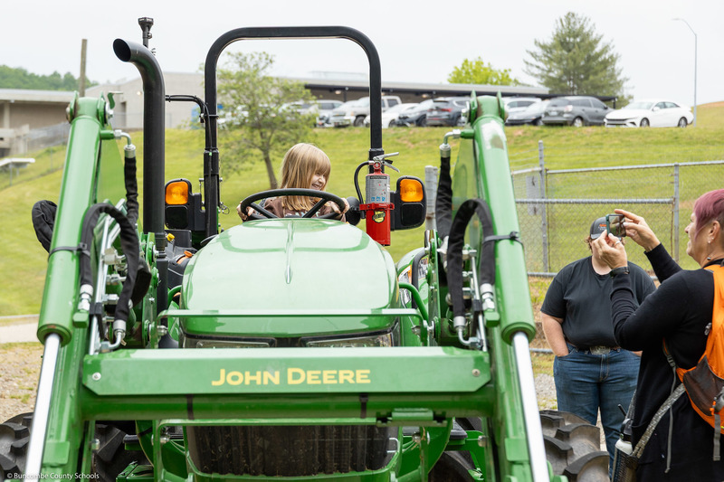 A student poses for a picture on a tractor.