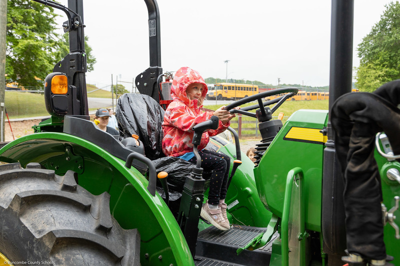 A student poses for a picture on a tractor.