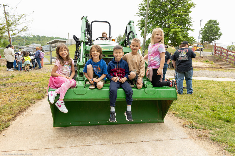 Students pose for a picture on a tractor.