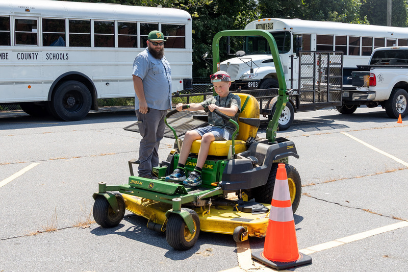 A student drive a tractor as a teacher observes.