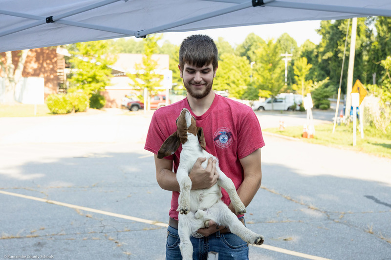 A high school student holds a goat.