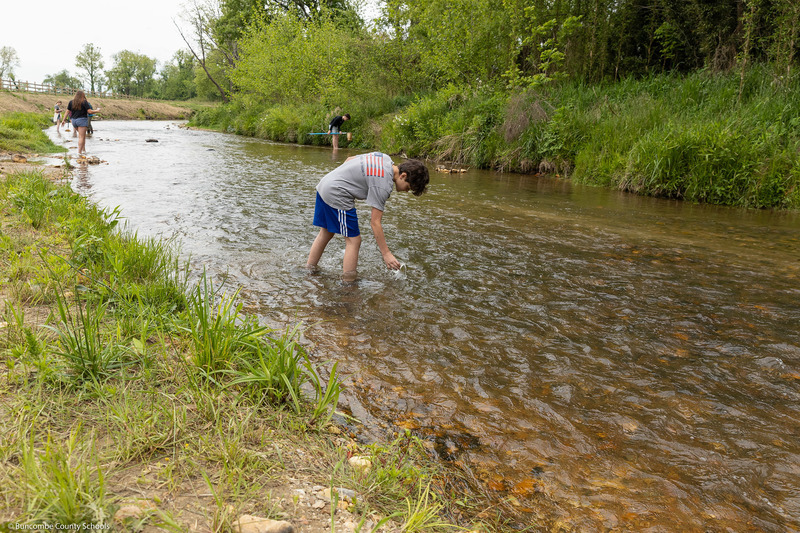 A student pours a water sample back into the creek.