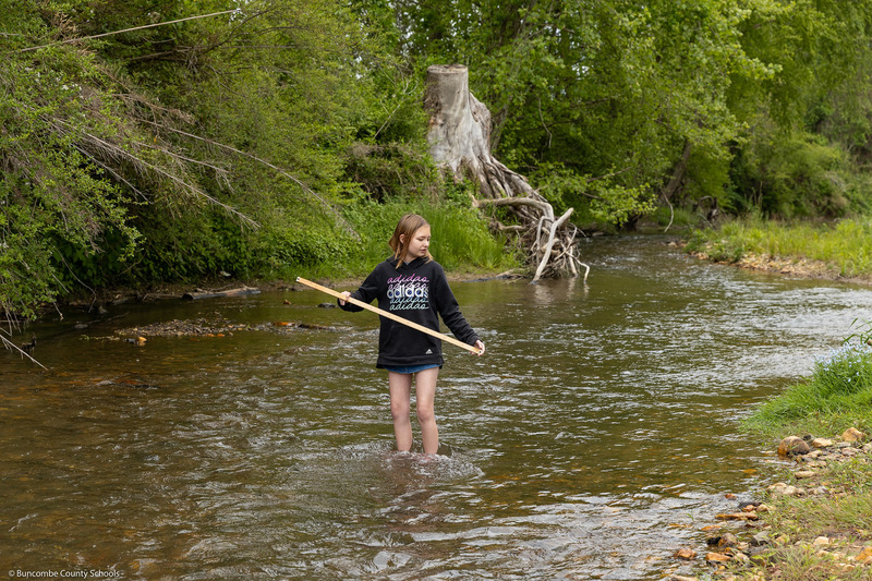A student holds a yardstick in the creek.